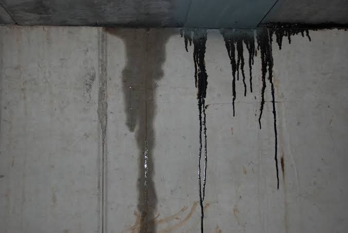 Dark water runoff and moisture staining on foundation concrete wall from concealed pipe breach